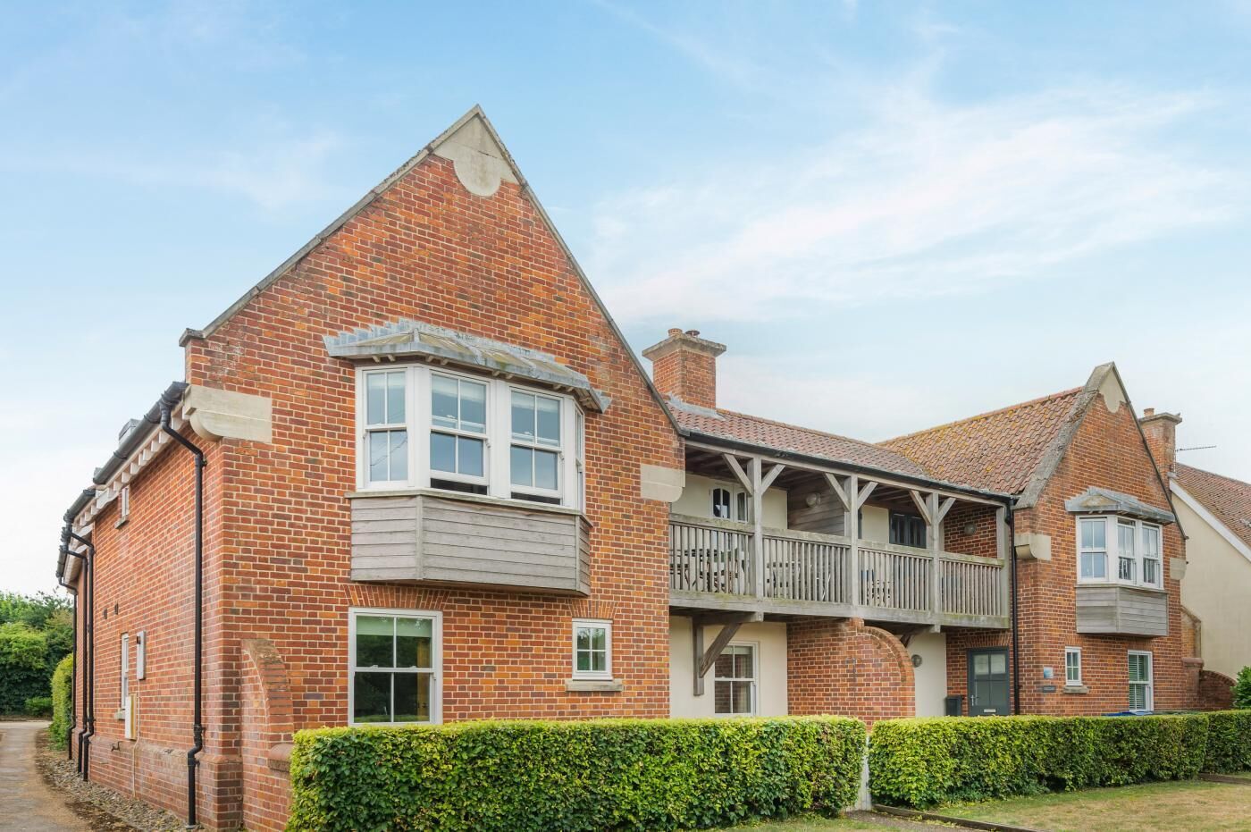 A two-story brick house with a balcony and a chimney.