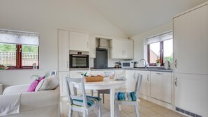 Uma cozinha compacta com armários brancos, uma mesa de jantar e cadeiras.
