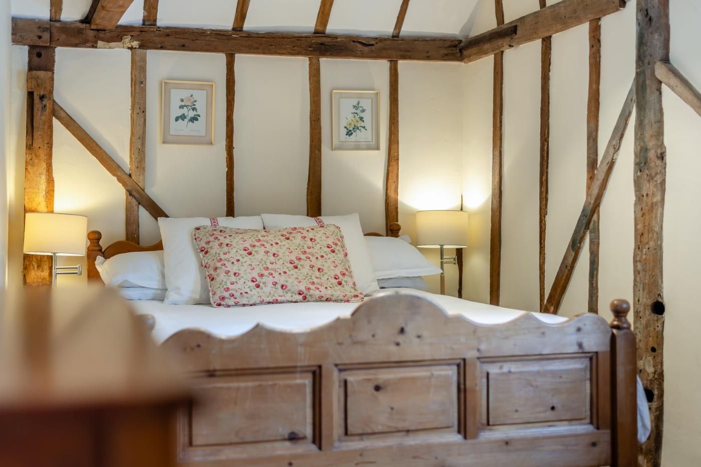 A bedroom with a wooden headboard, a bed with white linens, and two bedside lamps.