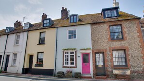 A row of terraced houses with distinct architectural styles, including a pink door and a stone facade. - 4 Bed in Rottingdean (oc-bbrott) (Brighton)