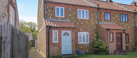 A two-story house with a stone facade, a tiled roof, and a front garden.