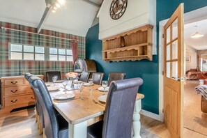 A dining area with a wooden table, leather chairs, a clock, and plaid-patterned wallpaper. - 5 Bed in Langton (oc-m32766) (Horncastle)