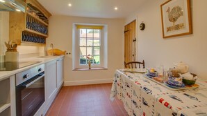 A kitchen with a dining table set for breakfast, a window with a view, and a clock on the wall. - 2 Bed in Docking (oc-913) (Docking)