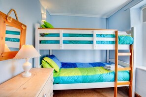 Une chambre avec un lit superposé, une tête de lit en bois, une table de chevet avec une lampe et un miroir au mur.
