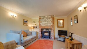 A cozy living room with a fireplace, a sofa, a TV, and a dining table. - 2 Bed in Docking (oc-913) (Docking)