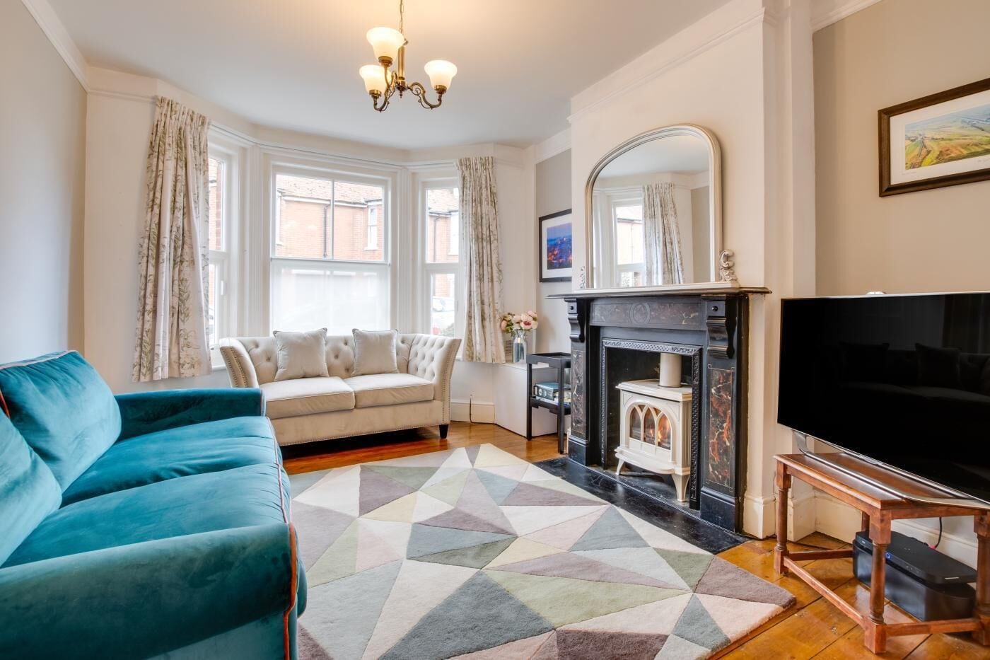 A living room with a sofa, a television, a fireplace, and a large window.