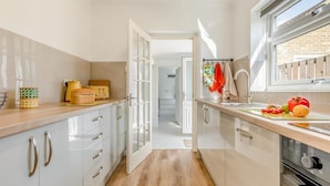 Een moderne keuken met witte kasten, een houten aanrecht en een raam.