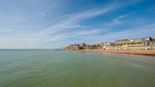 A coastal town with buildings along the beach, a clear sky, and calm waters.