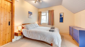 A bedroom with a bed, a nightstand, a window with curtains, a ceiling fan, and a wardrobe.