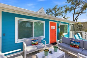 A bright blue house with a red door, white porch furniture, and colorful cushions. - ⭐Charming Triplex | Close to Beach | Pet Friendly | The Starfish Estate⭐ (Fort Myers Beach)