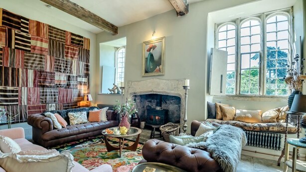 A cozy living room with a fireplace, leather sofas, and a patterned rug.