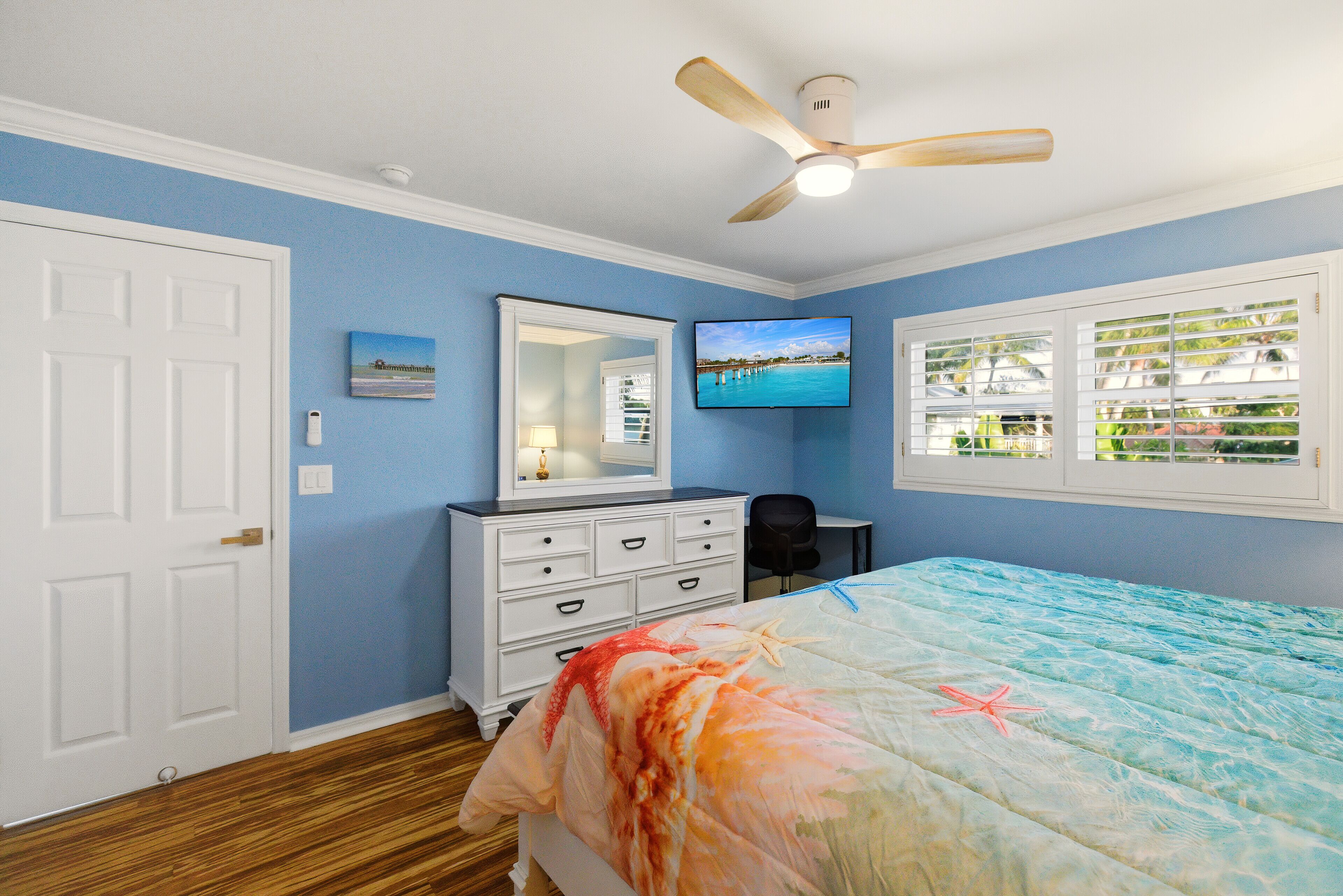 A bedroom with a bed, a dresser, a television, and a window with blinds.