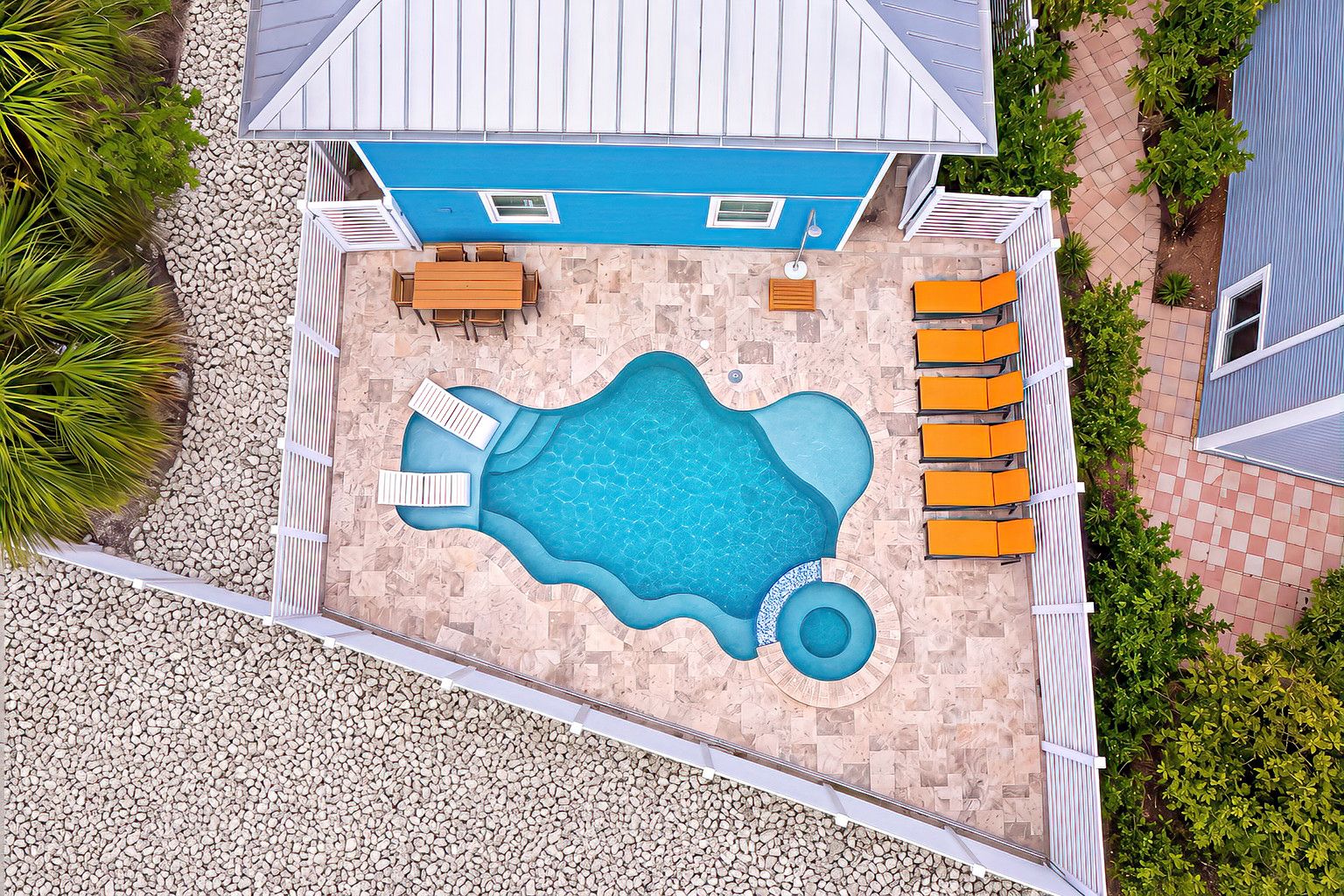 A rooftop pool with a blue interior, surrounded by a white fence, and adjacent to a blue building.