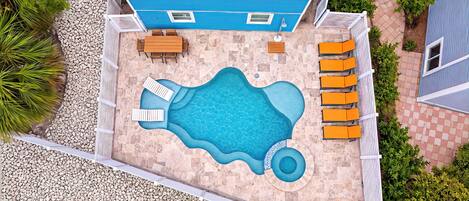 A rooftop pool with a blue interior, surrounded by a white fence, and adjacent to a blue building.