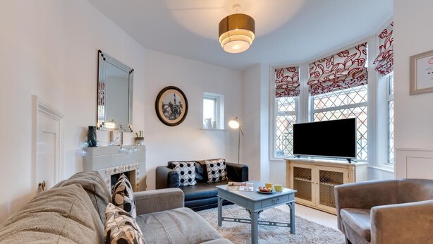 A living room with a sofa, armchair, coffee table, and a television. - 3 Bed in Broadstairs (oc-th006) (Broadstairs)