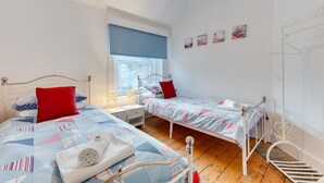 A bedroom with two beds, a window, and a coat rack. - 3 Bed in Broadstairs (oc-th006) (Broadstairs)