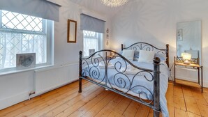 A bedroom with a metal bed frame, a large window with a view, a radiator, and a chandelier. - 3 Bed in Broadstairs (oc-th006) (Broadstairs)