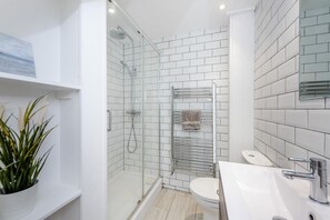 A modern bathroom with a glass-enclosed shower, a white toilet, and a sink with a chrome faucet. - 3 Bed in Sedlescombe (oc-c32764) (Sedlescombe)