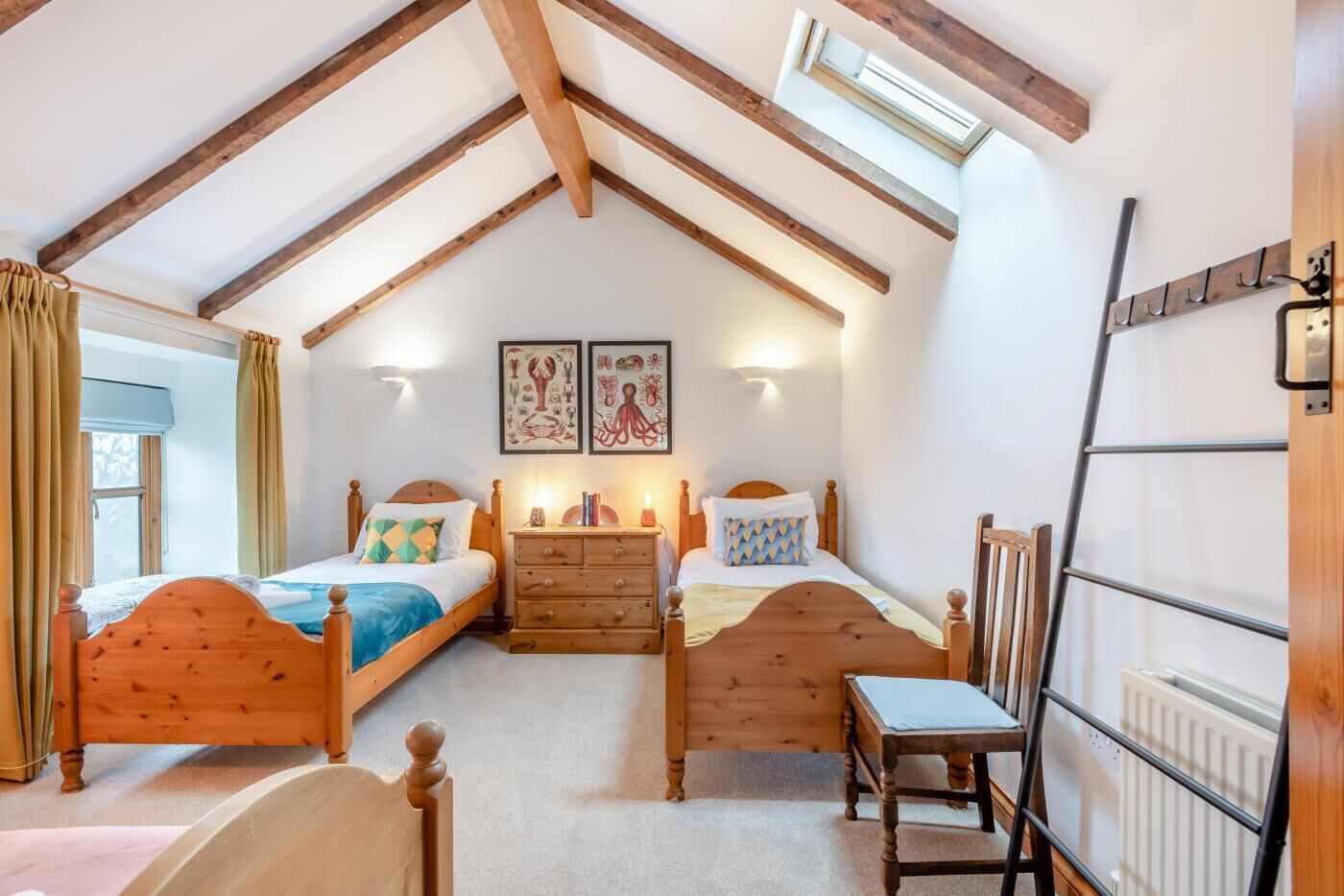 A cozy bedroom with two wooden beds, a wooden dresser, and a skylight.