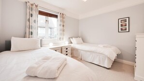 Ein Schlafzimmer mit zwei Betten, einem Schreibtisch und einer Kommode.