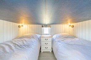Une chambre avec deux lits, une petite fenêtre et des lampes fixées au mur.