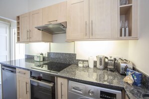 Een magnetron, een oven, een vaatwasser, kookgerei, borden en bestek