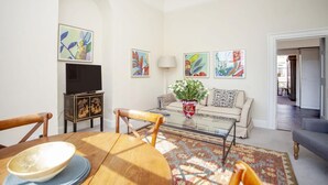 Ein Wohnzimmer mit einer Couch, einem Couchtisch, einem Fernseher und Kunstwerken an den Wänden.
