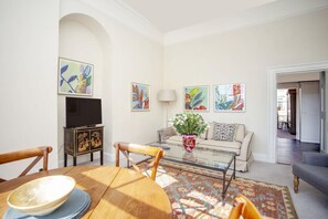 Ein Wohnzimmer mit einer Couch, einem Couchtisch, einem Fernseher und Kunstwerken an den Wänden.