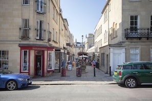 Eine Straße mit Gebäuden, einem roten Schaufenster und geparkten Autos.