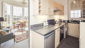 Eine moderne Küche mit hellen Holzschränken, einer Granitarbeitsplatte und einem eingebauten Geschirrspüler.