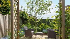 Een houten pergola met een tafel en twee stoelen eronder.