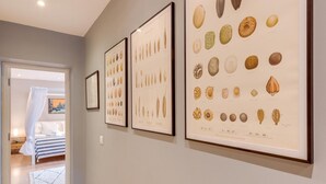 A hallway with framed marine life illustrations on the wall, leading to a bedroom with a bed and a nightstand. - 2 Bed in Broadstairs (oc-th017) (Broadstairs)
