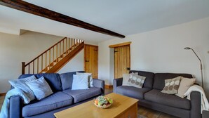 Un salon avec deux canapés, une table basse en bois et un escalier.