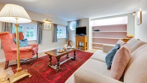 Una sala de estar con sofá, sillón, mesa de centro y mueble para televisión.