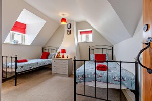 Ein Schlafzimmer mit zwei Betten, einer weißen Kommode und einer roten Lampe.