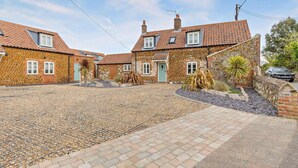 A stone house with a gravel driveway and a paved entrance. - 4 Bed in Ringstead (oc-1672) (Ringstead)