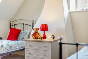 A child's bedroom with a bed, a nightstand, a teddy bear, a lamp, and an alarm clock. - 4 Bed in Ringstead (oc-1672) (Ringstead)