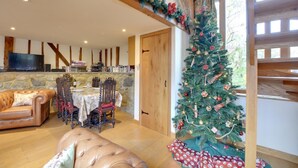 A cozy living room with a stone fireplace, a wooden ceiling, a Christmas tree, and a dining area with a table and chairs. - 2 Bed in Cranbrook (oc-cb594) (Cranbrook)