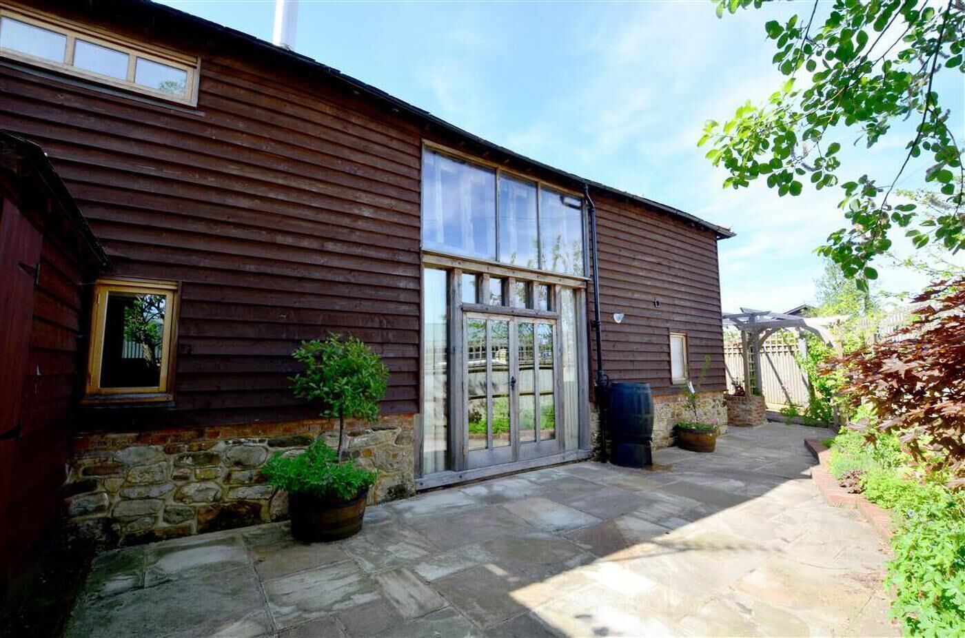 A wooden building with a large glass door and windows, stone steps, and potted plants.