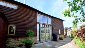 A wooden building with a large glass door and windows, stone steps, and potted plants. - 2 Bed in Cranbrook (oc-cb594) (Cranbrook)
