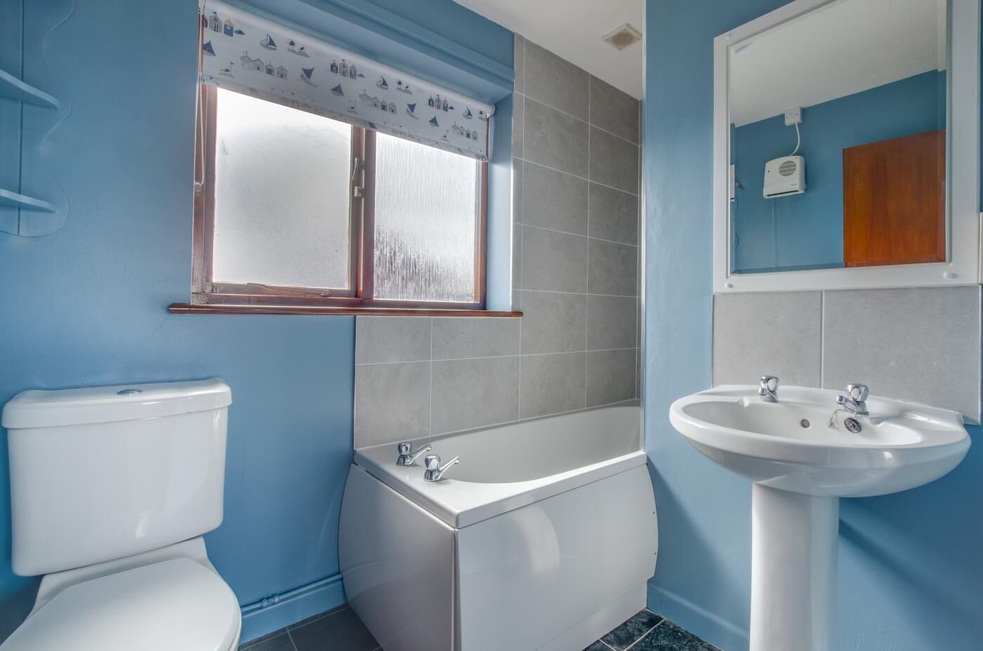 Et badeværelse med toilet, badekar og vask.