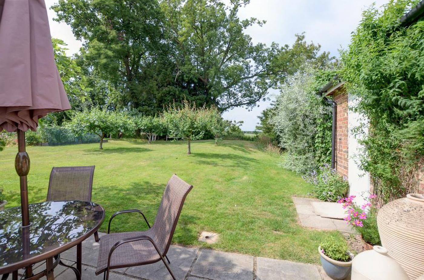 Un patio con tavolo e sedie, immerso nel verde e alberato.