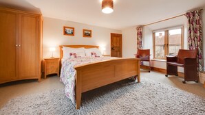 A bedroom with a wooden bed, a nightstand, a chair, a desk, a wardrobe, and a window with curtains. - 4 Bed in Roughton (oc-1435) (Roughton)