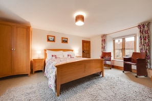 A bedroom with a wooden bed, a nightstand, a chair, a desk, a wardrobe, and a window with curtains. - 4 Bed in Roughton (oc-1435) (Roughton)