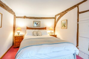 Un dormitorio con una cama de madera con dosel, dos mesitas de noche con lámparas y dos cuadros colgados en la pared.