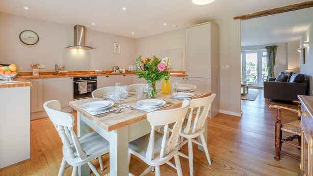 A modern kitchen with a dining area, wooden flooring, and a view to the living room. - 3 Bed in Staplecross (oc-rh1162) (Sedlescombe)