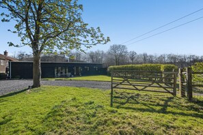 Ein Wohnhaus mit Garten, Holztor und Baum.