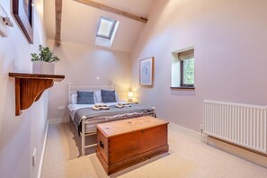 A bedroom with a bed, bedside table, a wooden chest, a skylight, a radiator, and a window. - 3 Bed in Briston (oc-1167) (Briston)