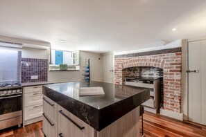 Una cocina moderna con una isla central, horno de ladrillo y estufa de acero inoxidable.