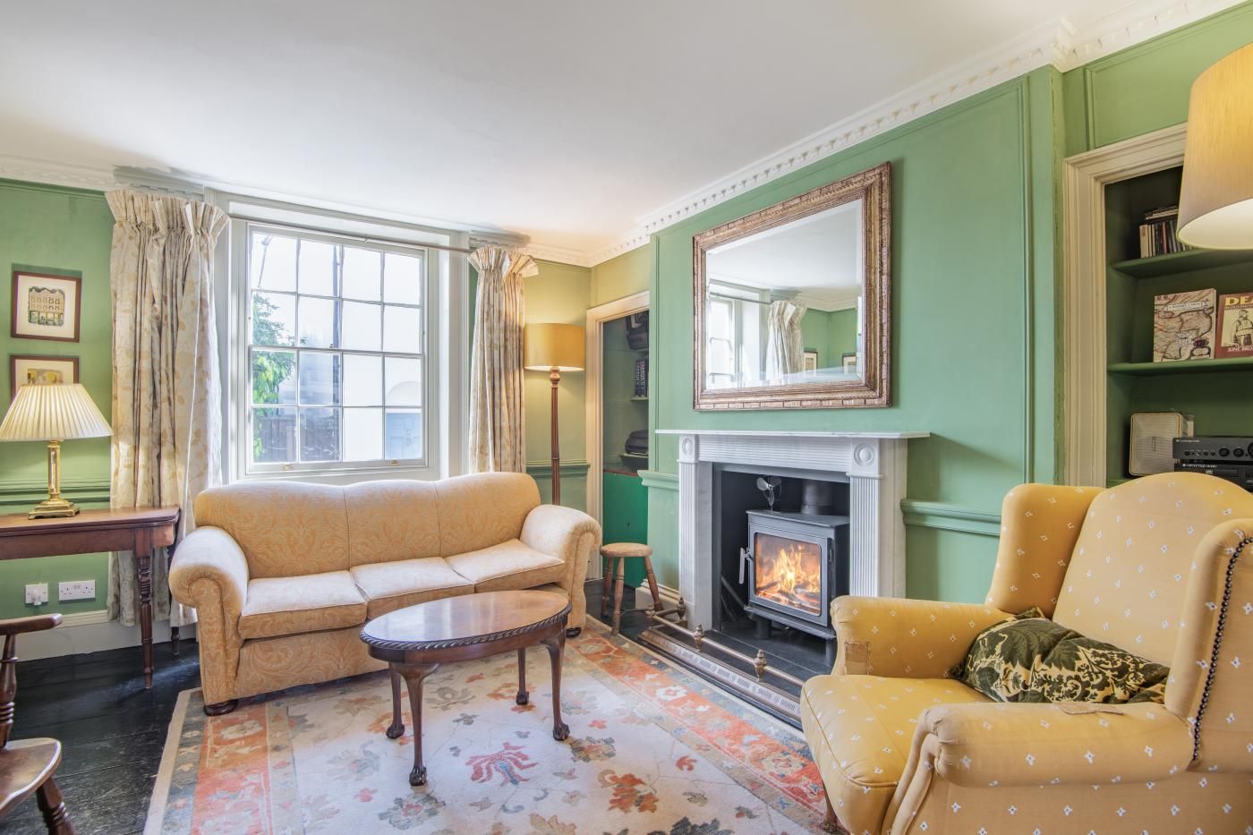 Een klassieke woonkamer met een open haard, groene wanden en tijdloze meubels.